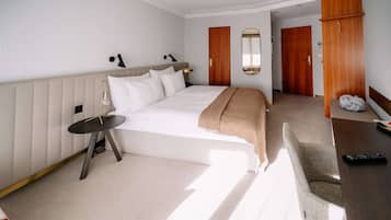 Ein Hotelzimmer mit Bett, Nachttisch, Lampe und Schreibtisch mit Stuhl.