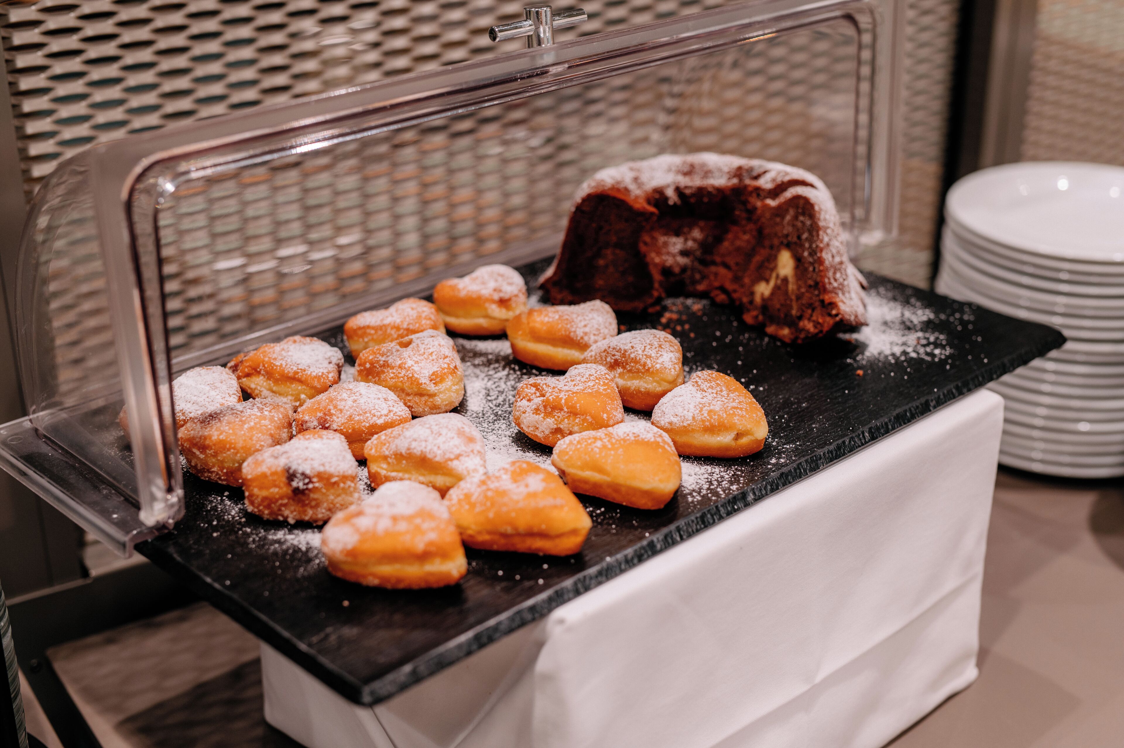 A buffet with a variety of pastries, including heart-shaped doughnuts and a bundt cake.