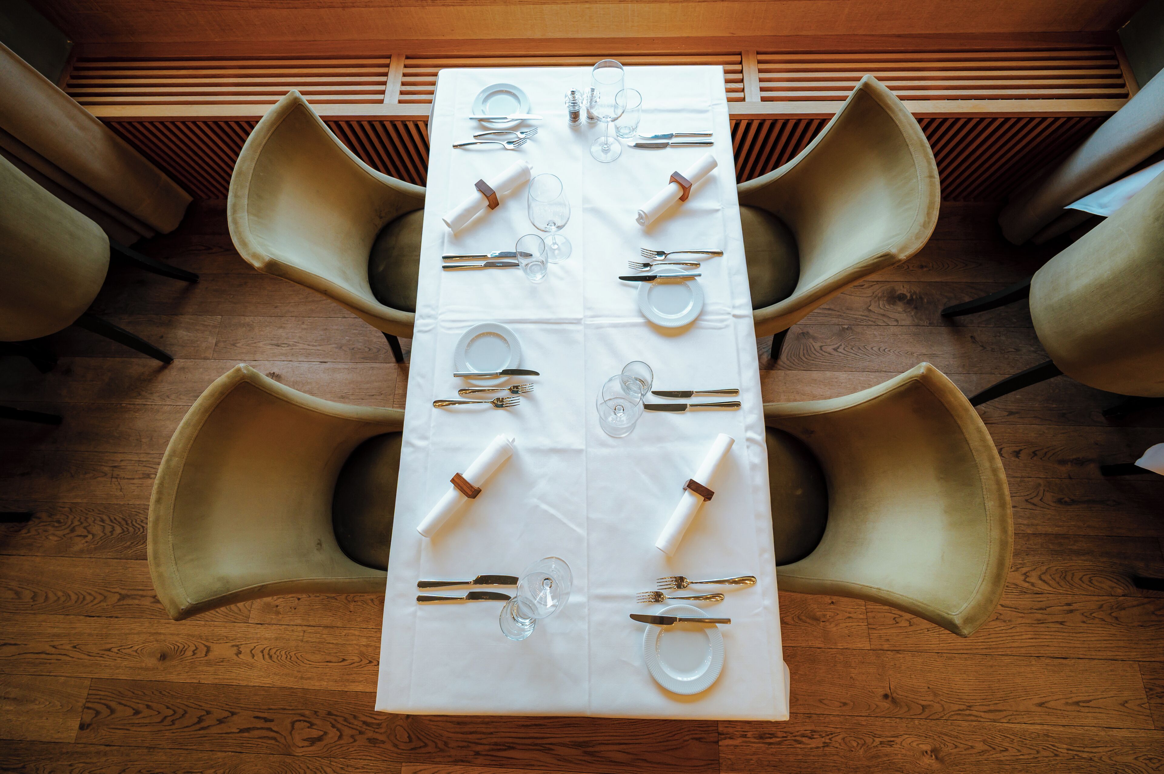 A dining table set with cutlery and glasses, surrounded by chairs.
