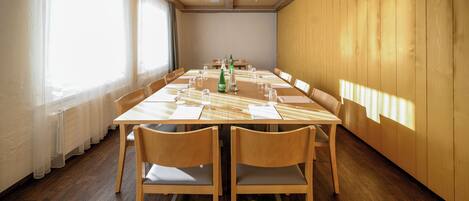 A conference room with a long table, chairs, and a window with blinds.