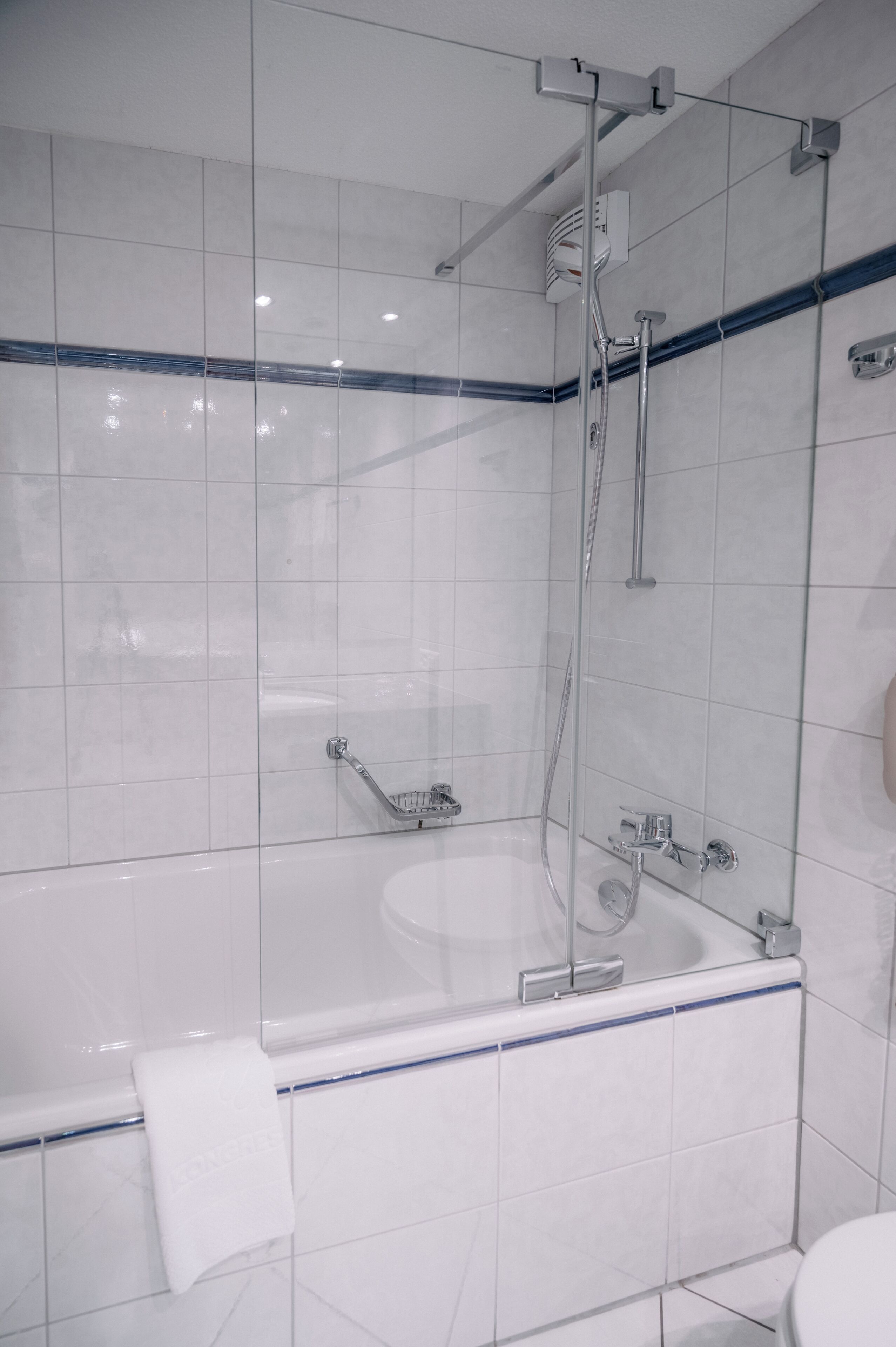Een moderne badkamer met een douchecabine van glas, een witte badkuip en een handdoekrek.
