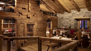 A rustic wooden interior with stone walls, wooden tables, and benches. - Unique Hotel Post (Zermatt)