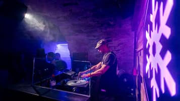Una cabina de DJ con una computadora portátil, tocadiscos y una botella de Evian.