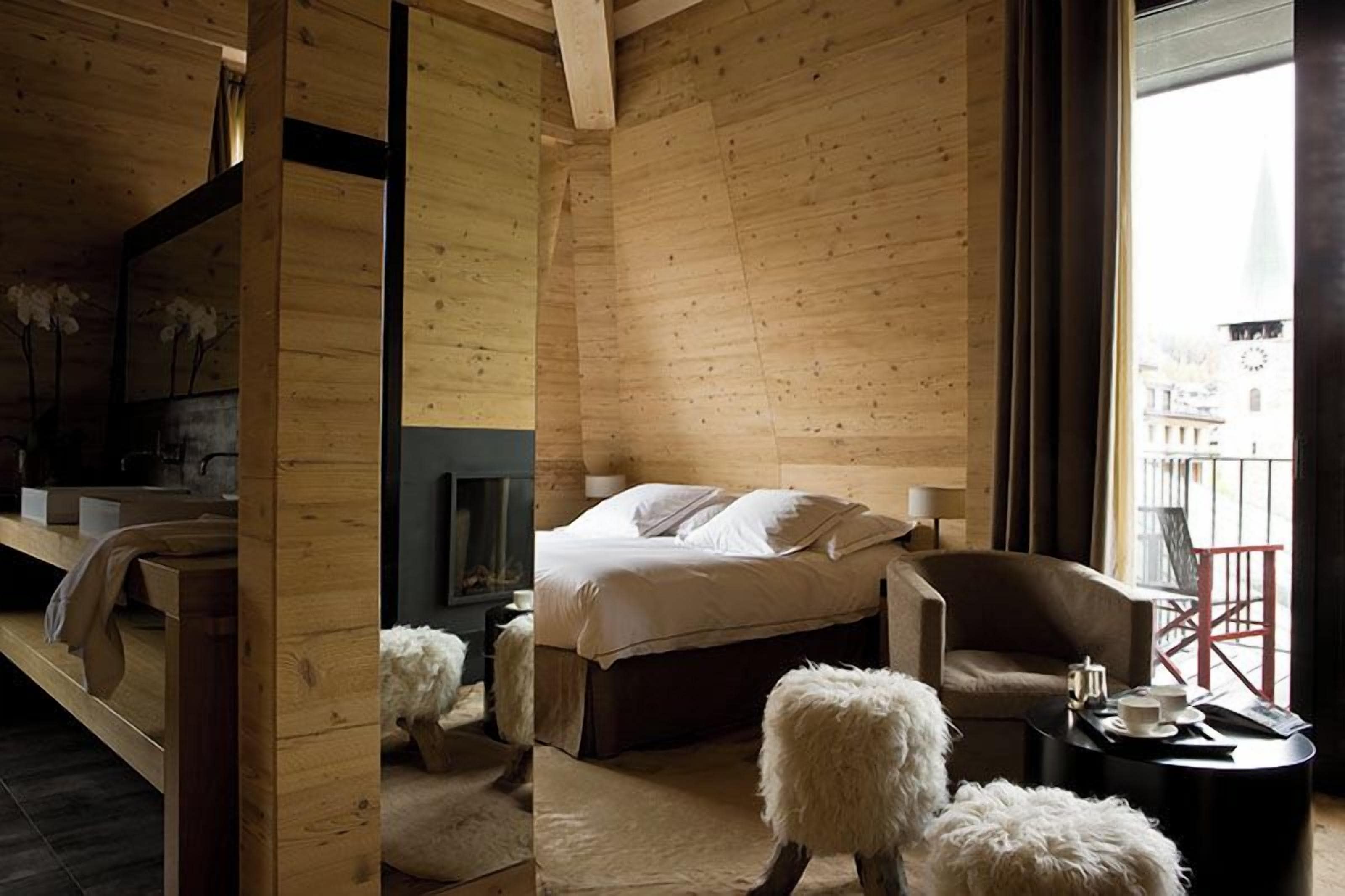 A wooden interior with a bed, a chair, and a small table.