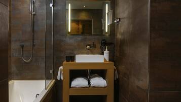 Une salle de bain moderne avec une baignoire, une douche à parois de verre, un meuble-lavabo en bois et un miroir.