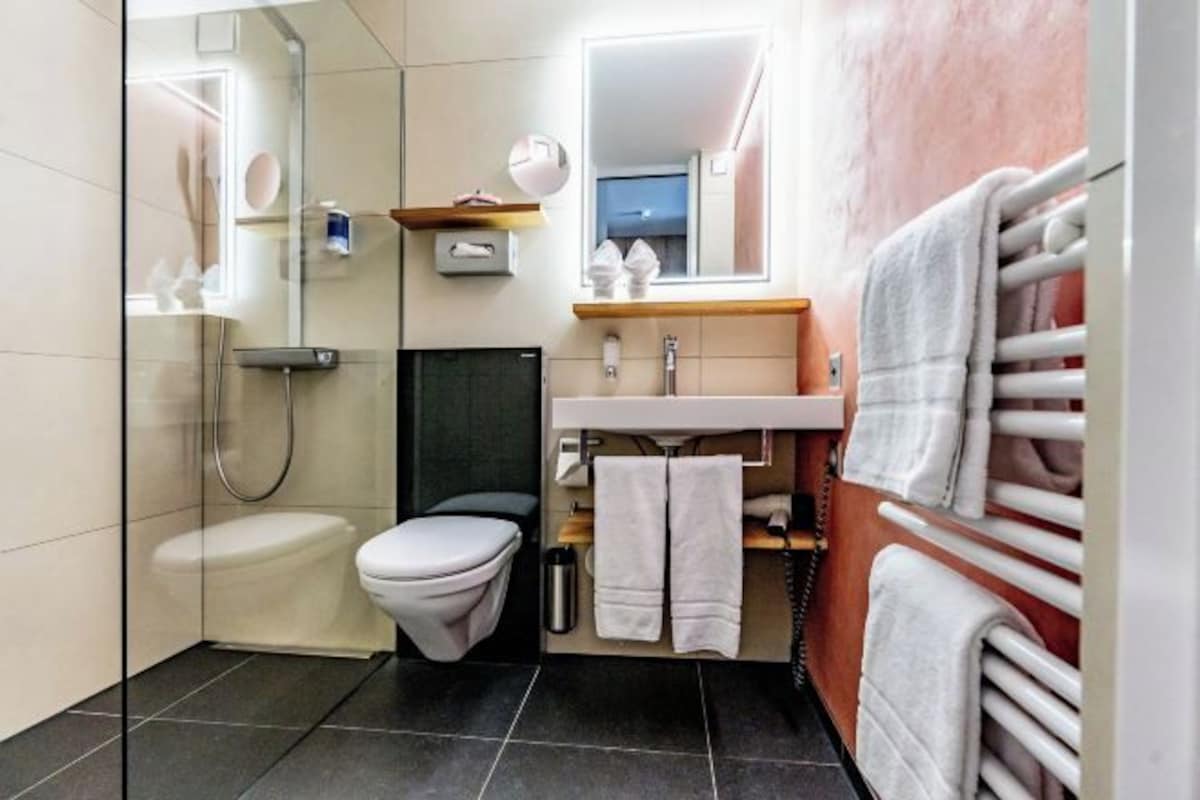 A modern bathroom with a toilet, shower, and sink.