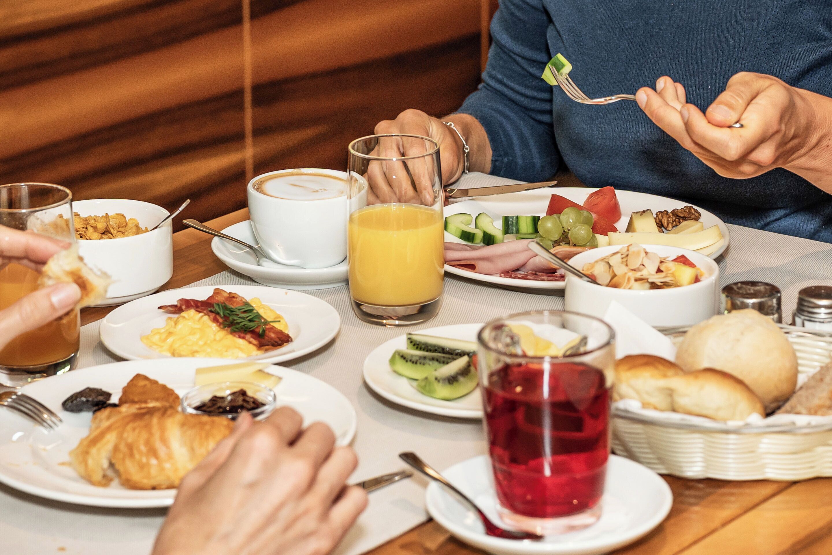 A breakfast setting with various dishes, including eggs, toast, and fruit, and beverages like coffee and orange juice.