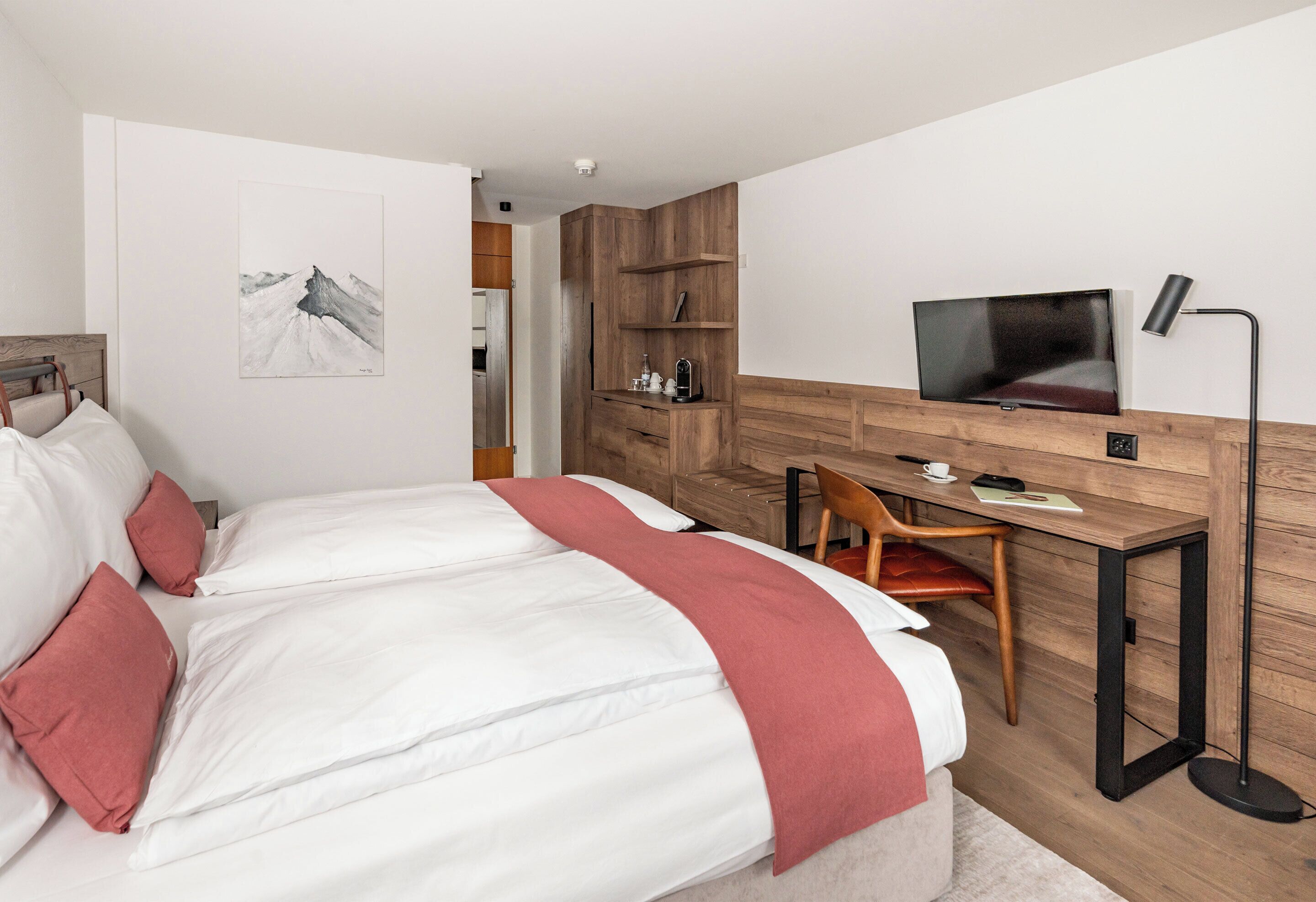 Un dormitorio moderno con cama, escritorio, silla, televisor y armario.