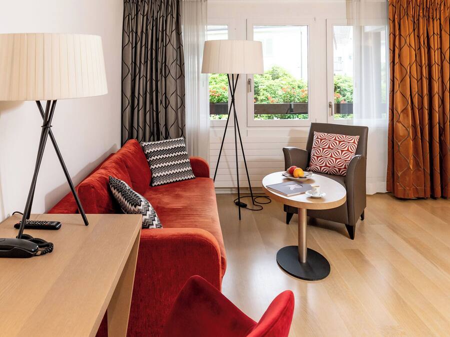 Ein modernes Wohnzimmer mit einem roten Sofa, einem Couchtisch und zwei Stehlampen.