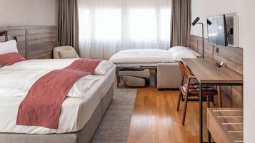 A hotel room with two beds, a desk, a chair, and a TV.
