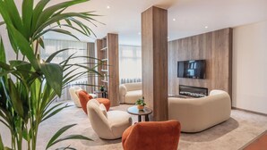 Ein modernes Wohnzimmer mit einer Couch, Sesseln und einem Fernseher.