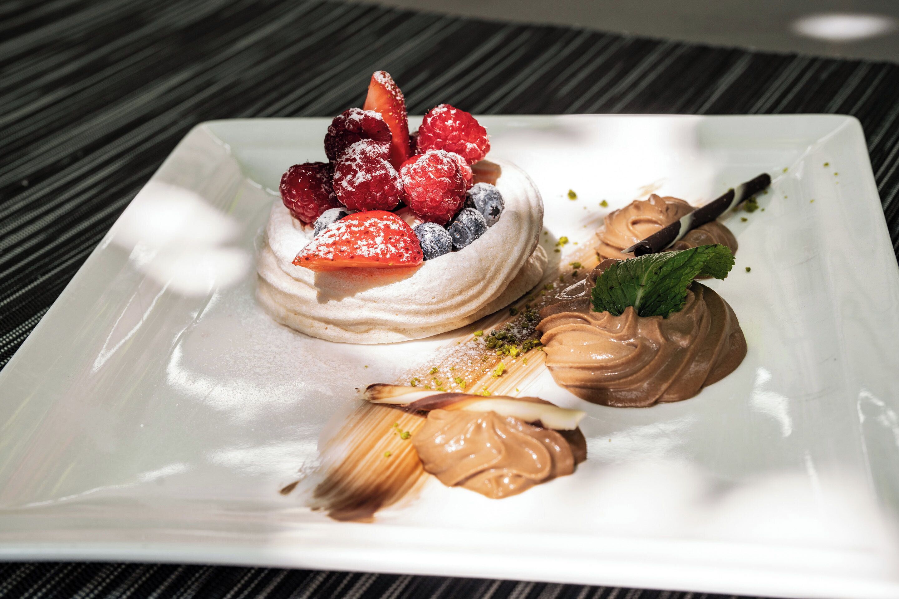 A dessert plate with meringue, fresh berries, and chocolate sauce.