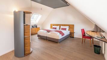Un dormitorio moderno con techo estilo loft, una cama con cabecera de madera, una silla roja y un escritorio con lámpara.