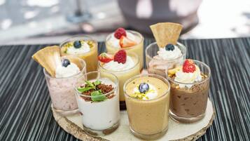 Een dienblad met zes toetjes en diverse toppings, op een houten plank.