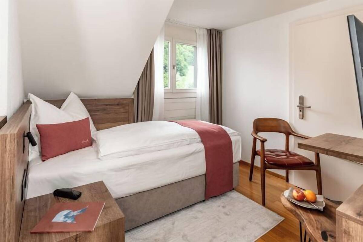 Une chambre à coucher avec un lit, un bureau, une chaise et une fenêtre.