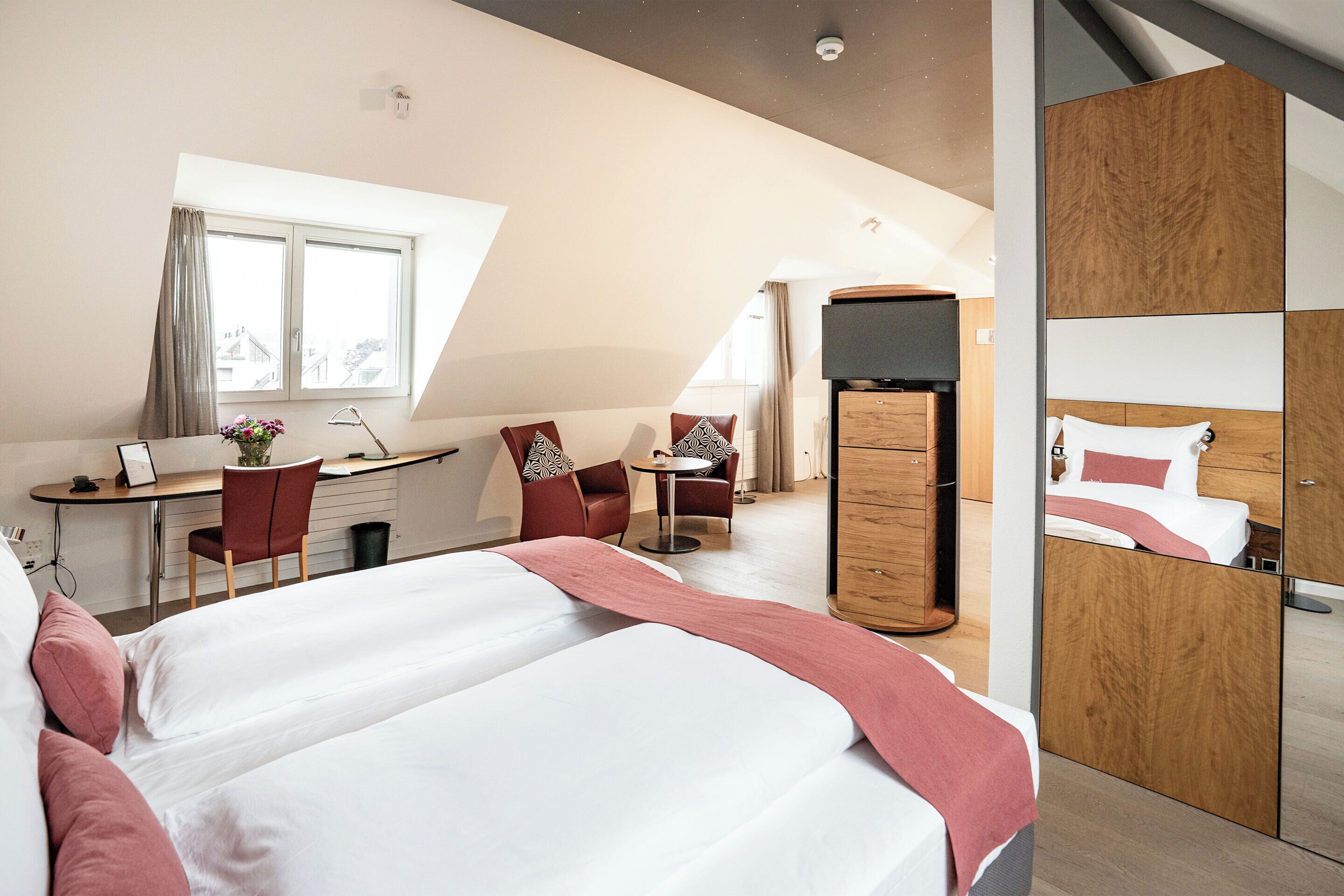 Une chambre d’hôtel moderne équipée d’un grand lit, d’un bureau, d’une chaise, d’une petite table et d’une armoire.