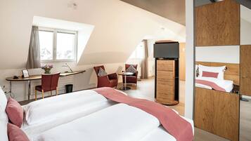 Une chambre d’hôtel moderne équipée d’un grand lit, d’un bureau, d’une chaise, d’une petite table et d’une armoire.