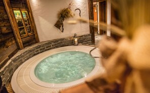 A hot tub with a stone wall and wooden beams. - Hotel Bellerive (Zermatt)