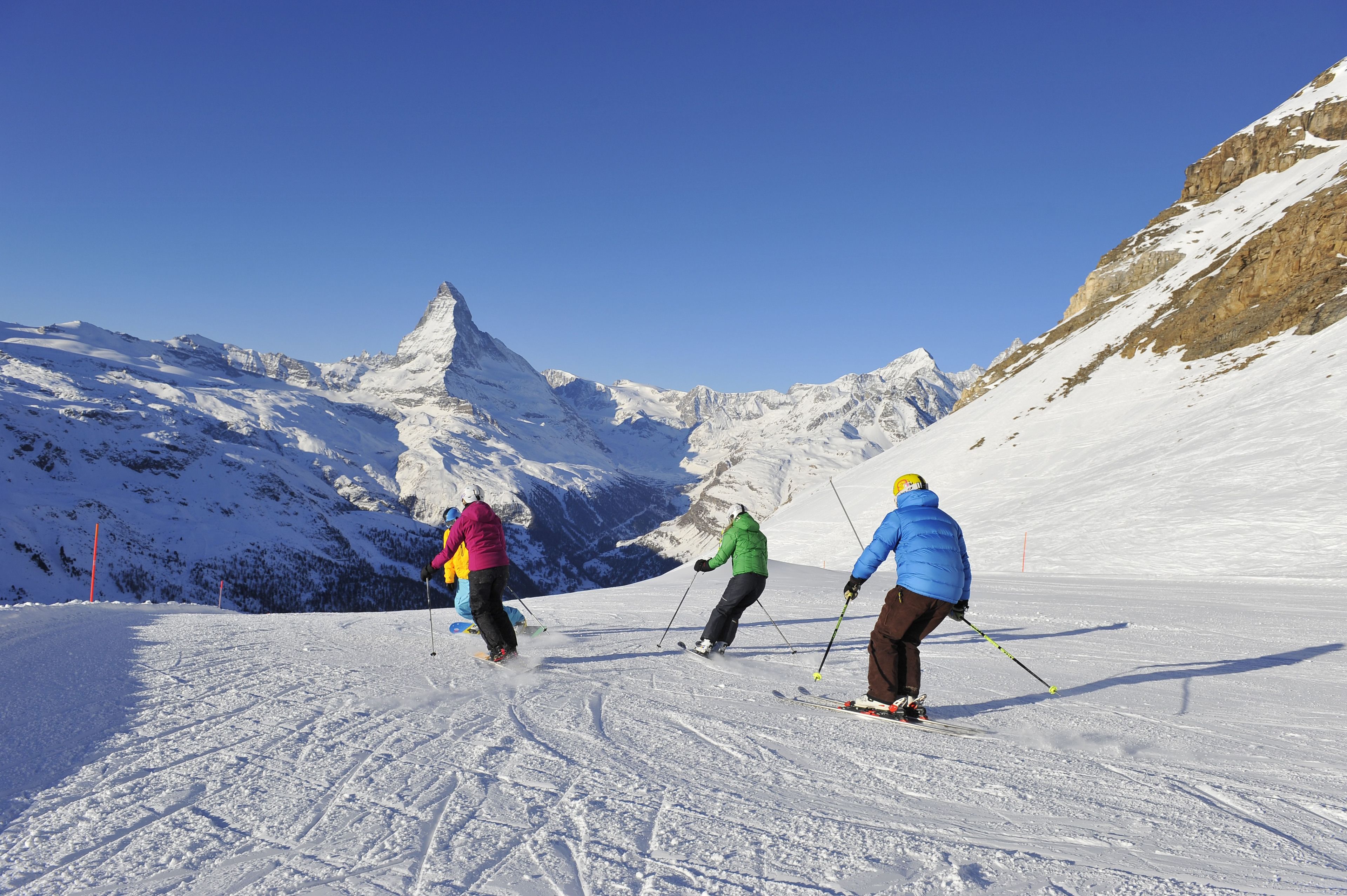 Skiers on a snowy slope with a mountain in the background.