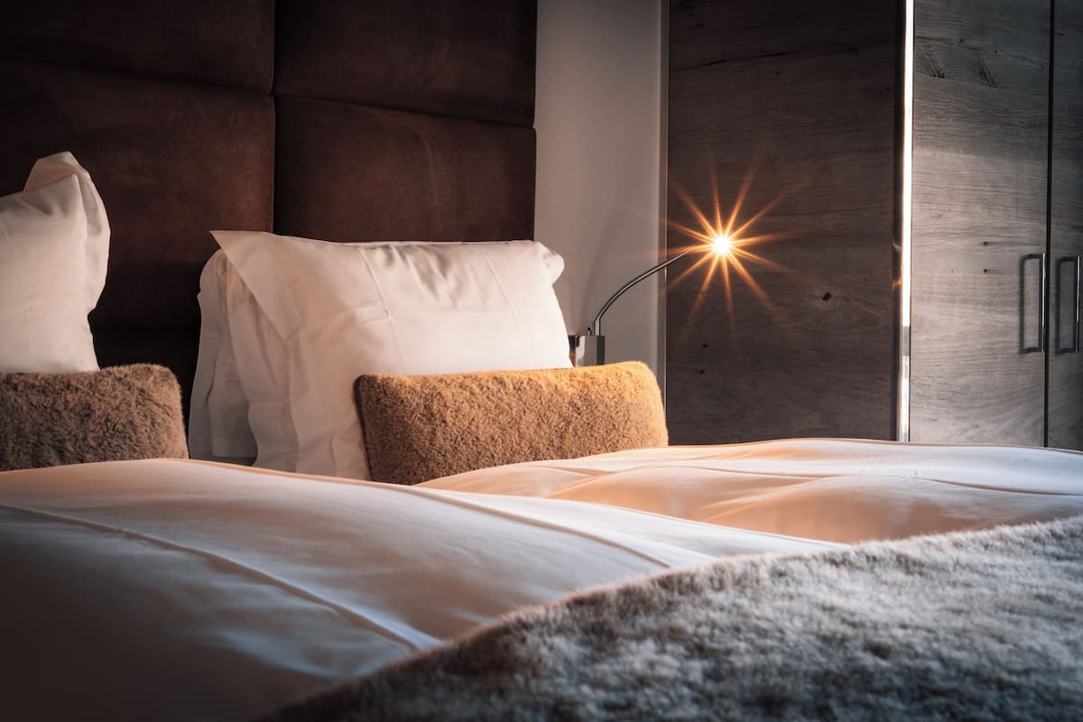 A modern bedroom with a large bed, a headboard, and a nightstand with a lamp.