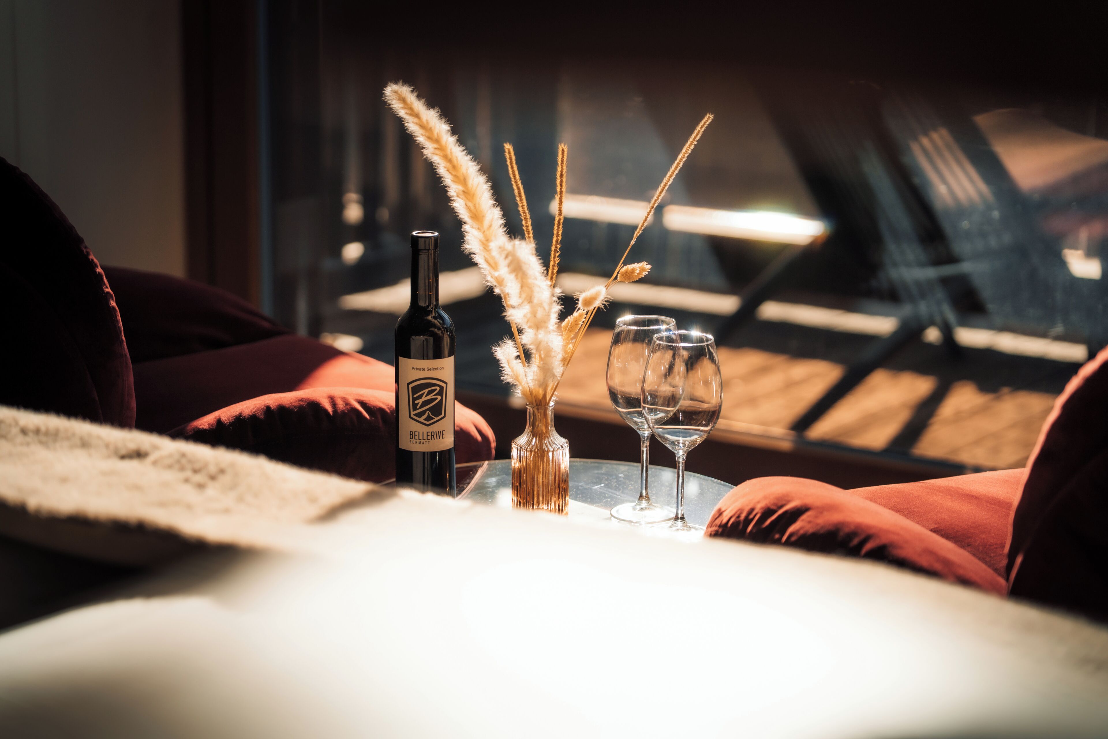 Ein Tisch mit einer Flasche, einer Vase mit Trockenpflanzen und zwei Gläsern.