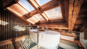 Ein modernes Badezimmer mit einer freistehenden Badewanne, Dachfenstern und einer Holzbodenverkleidung.