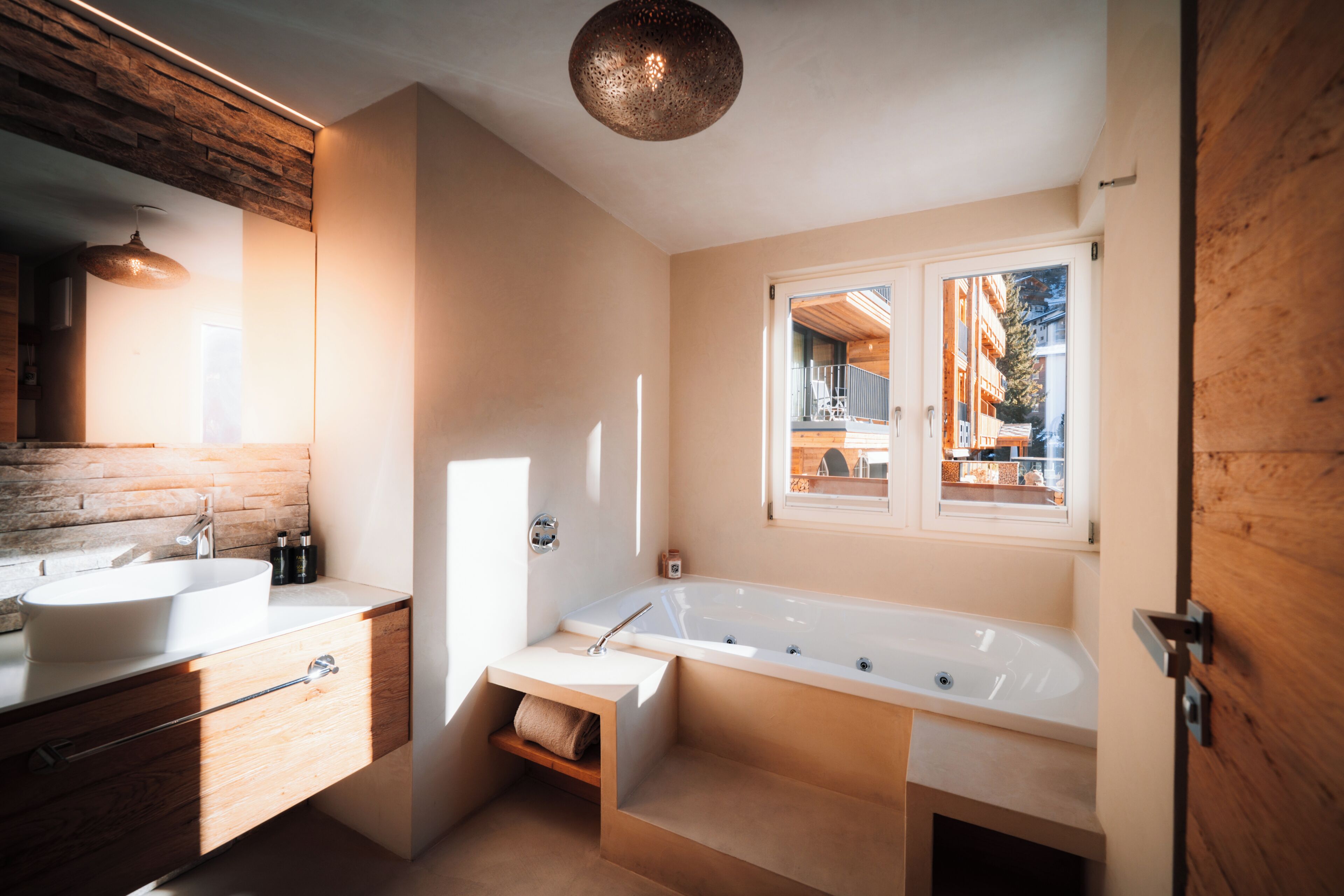 Un baño moderno con una bañera grande, dos lavamanos y un tocador de madera.