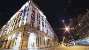 A historic building with a prominent 'royal' sign, large arched windows, and a tram line passing by. - Royal Hotel (Basel)
