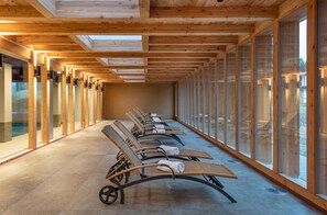 A row of sun loungers with towels, wooden ceiling beams, and large windows. - Sunstar Hotel Lenzerheide (Vaz-Obervaz)
