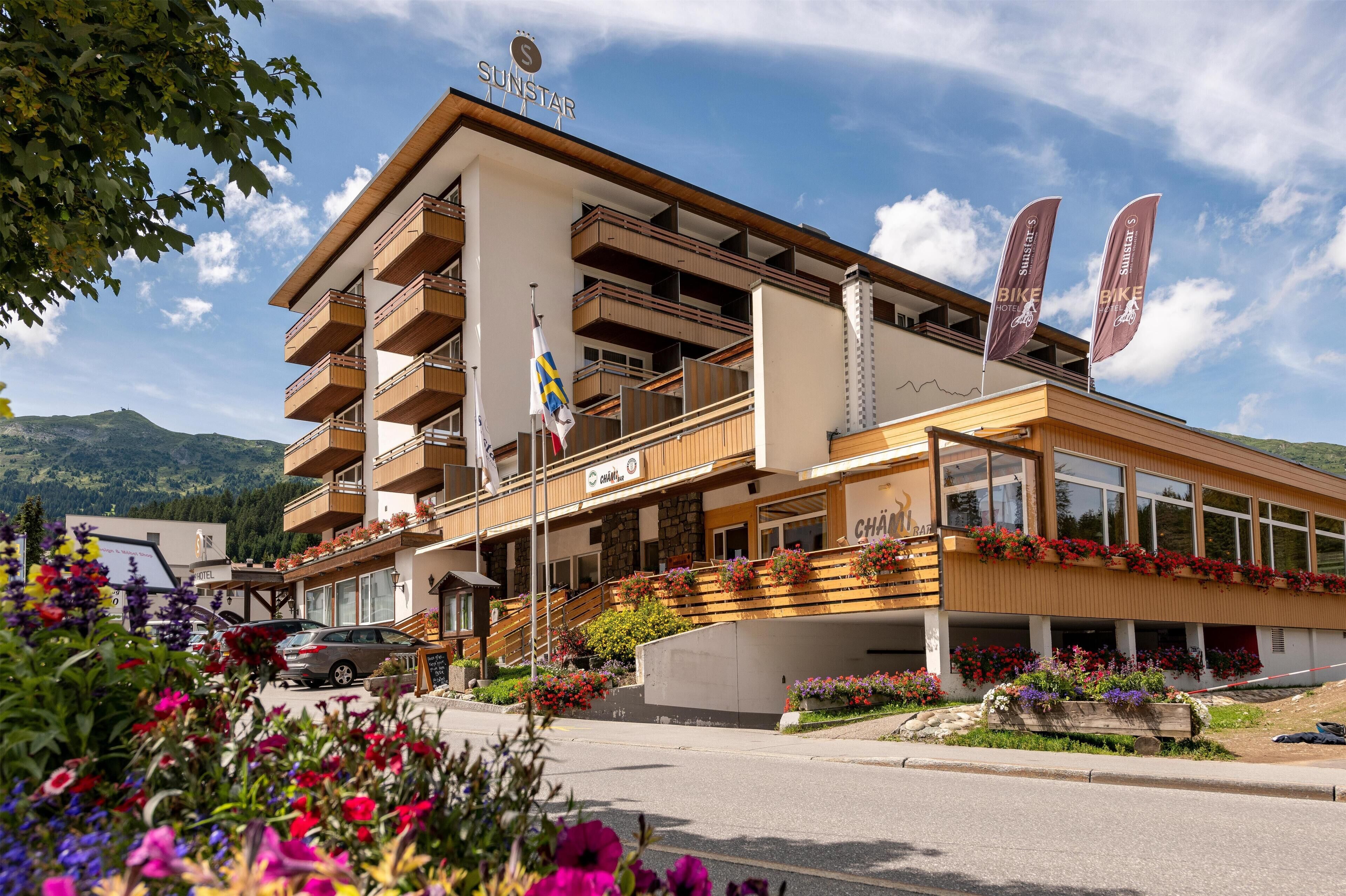A hotel with multiple balconies, a sign reading "SUNSTAR," and flags.