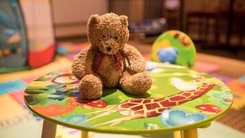 Un oso de peluche marrón sentado sobre una mesa colorida con diseño de jirafa.