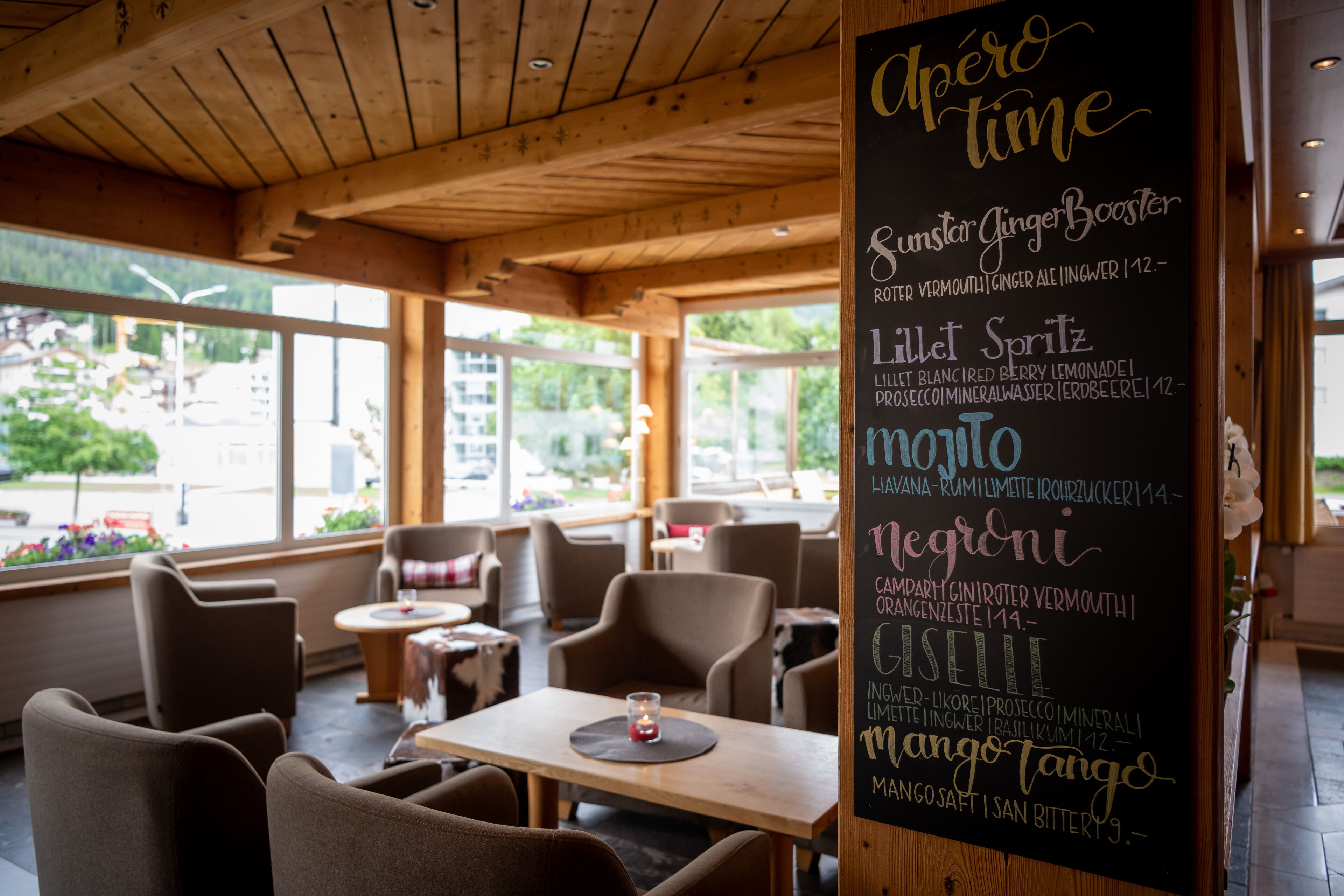A cozy café with wooden furniture and a chalkboard menu listing various drinks.