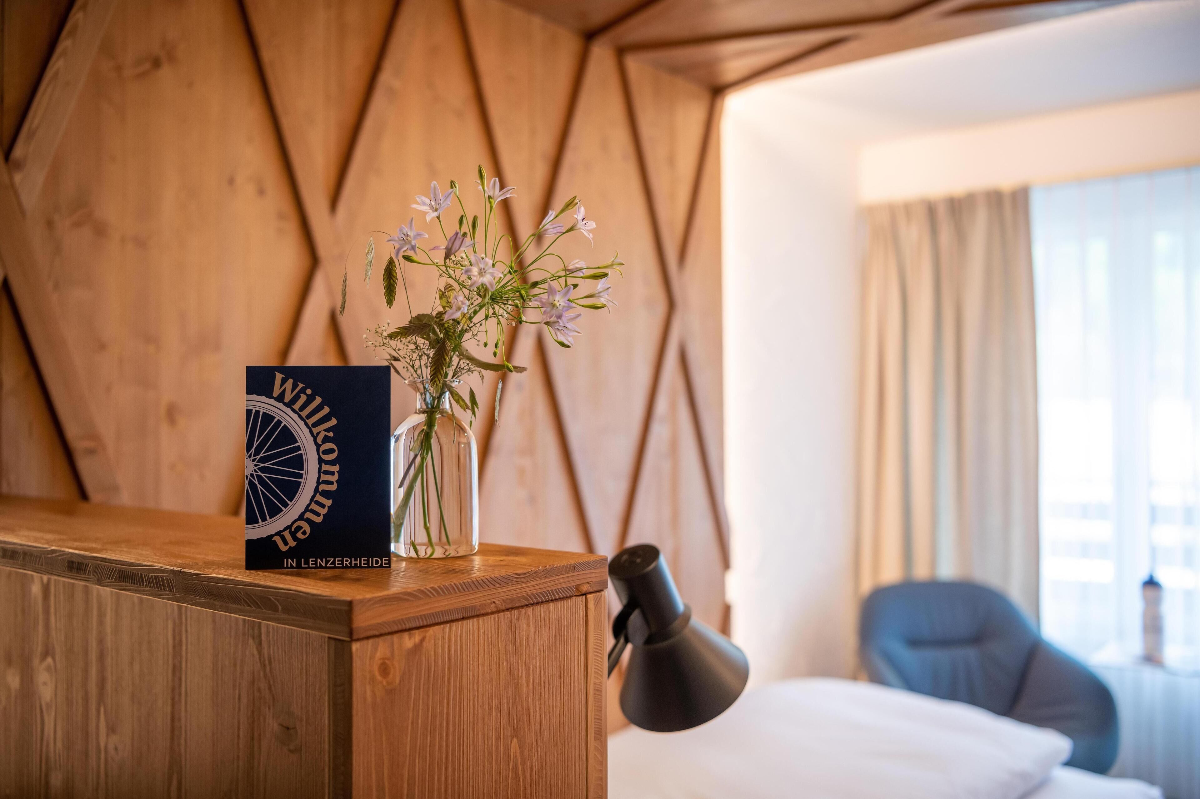 Ein Holztisch mit einem Buch mit dem Titel 'Winklerheim' und einer Vase mit Blumen.