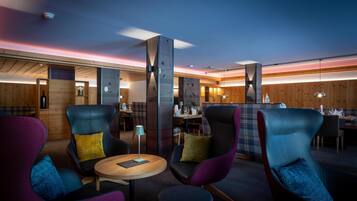 Un espace lounge moderne doté de sièges confortables, d’un bar en bois et d’un éclairage d’ambiance.