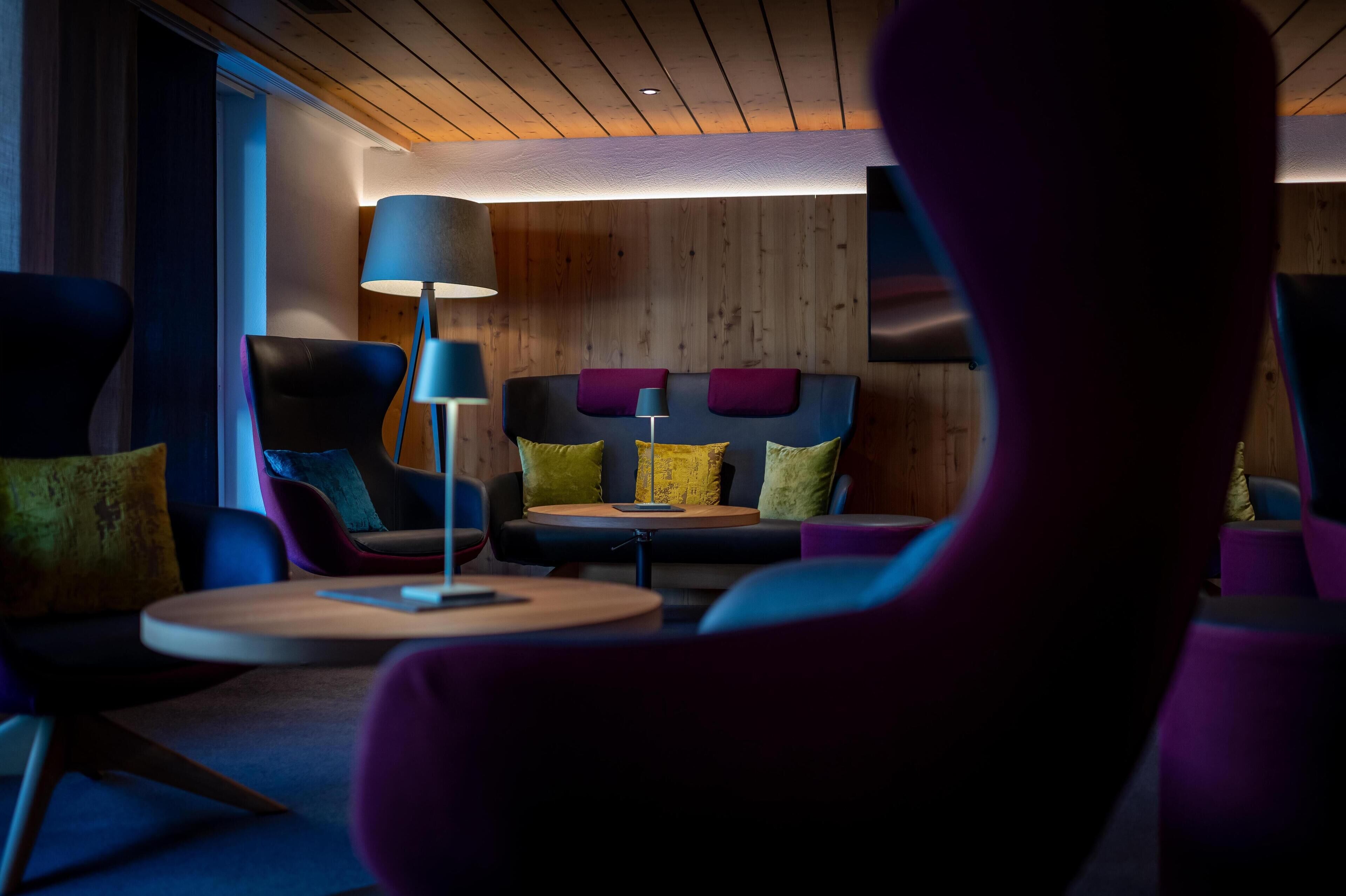 Un espace de détente moderne avec un plafond en bois, un canapé agrémenté de coussins colorés et une table ronde.