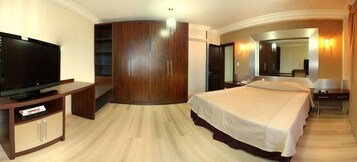 Una habitación de hotel con una cama grande, televisión, armario y espejo.
