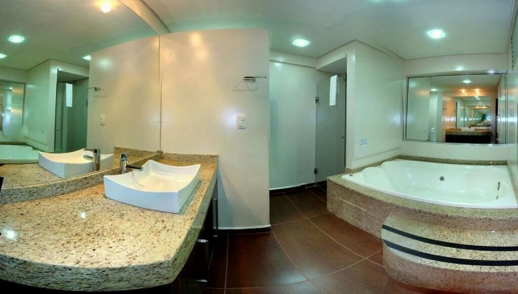 A modern bathroom with a granite countertop, a large bathtub, and a mirror.
