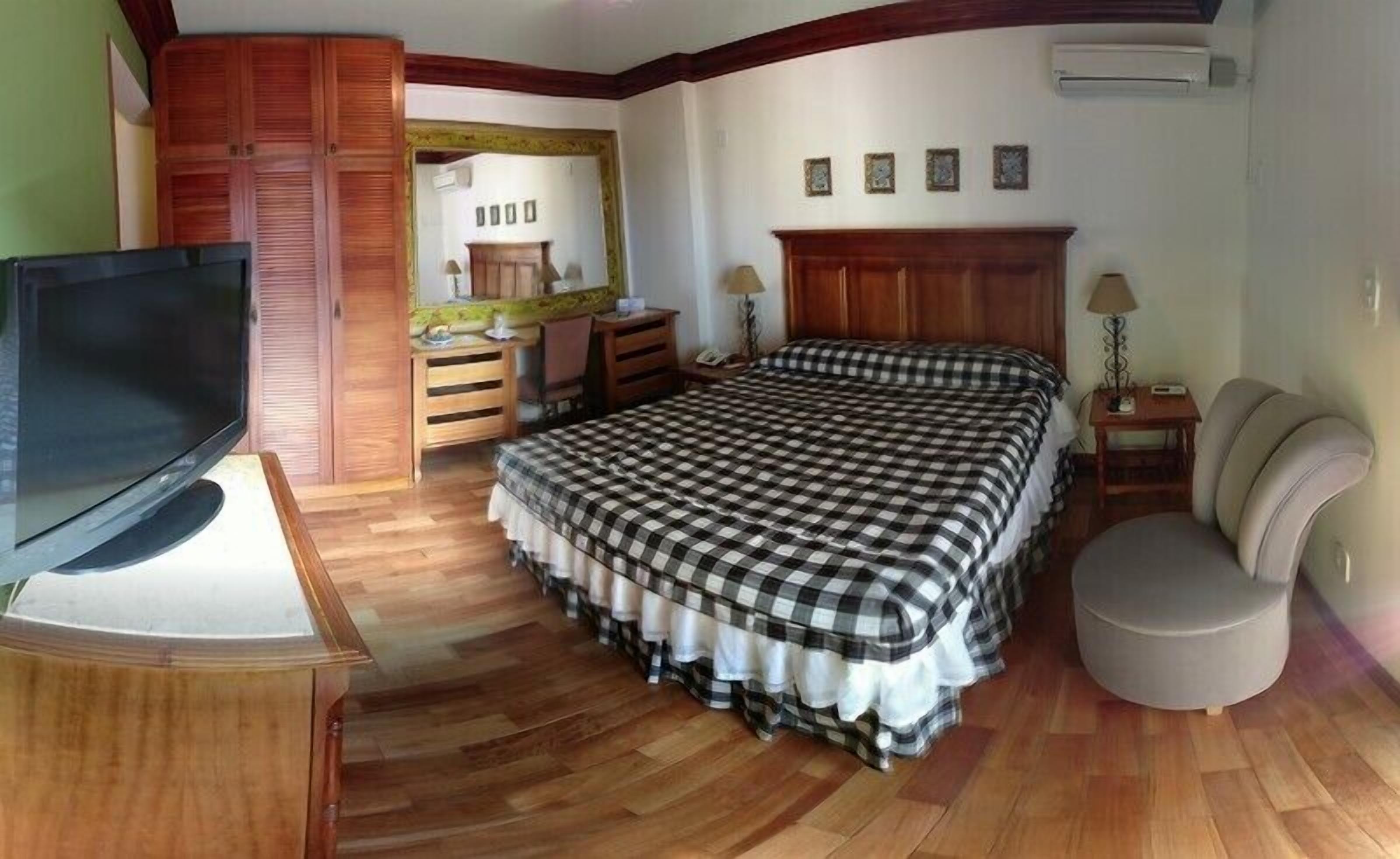 Un dormitorio con cama, televisión, escritorio, silla y armario.