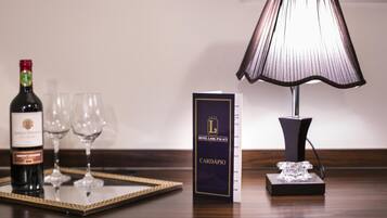 Habitación de hotel con una botella de vino, dos copas de vino, una lámpara y una tarjeta del Hotel Lang Palace.