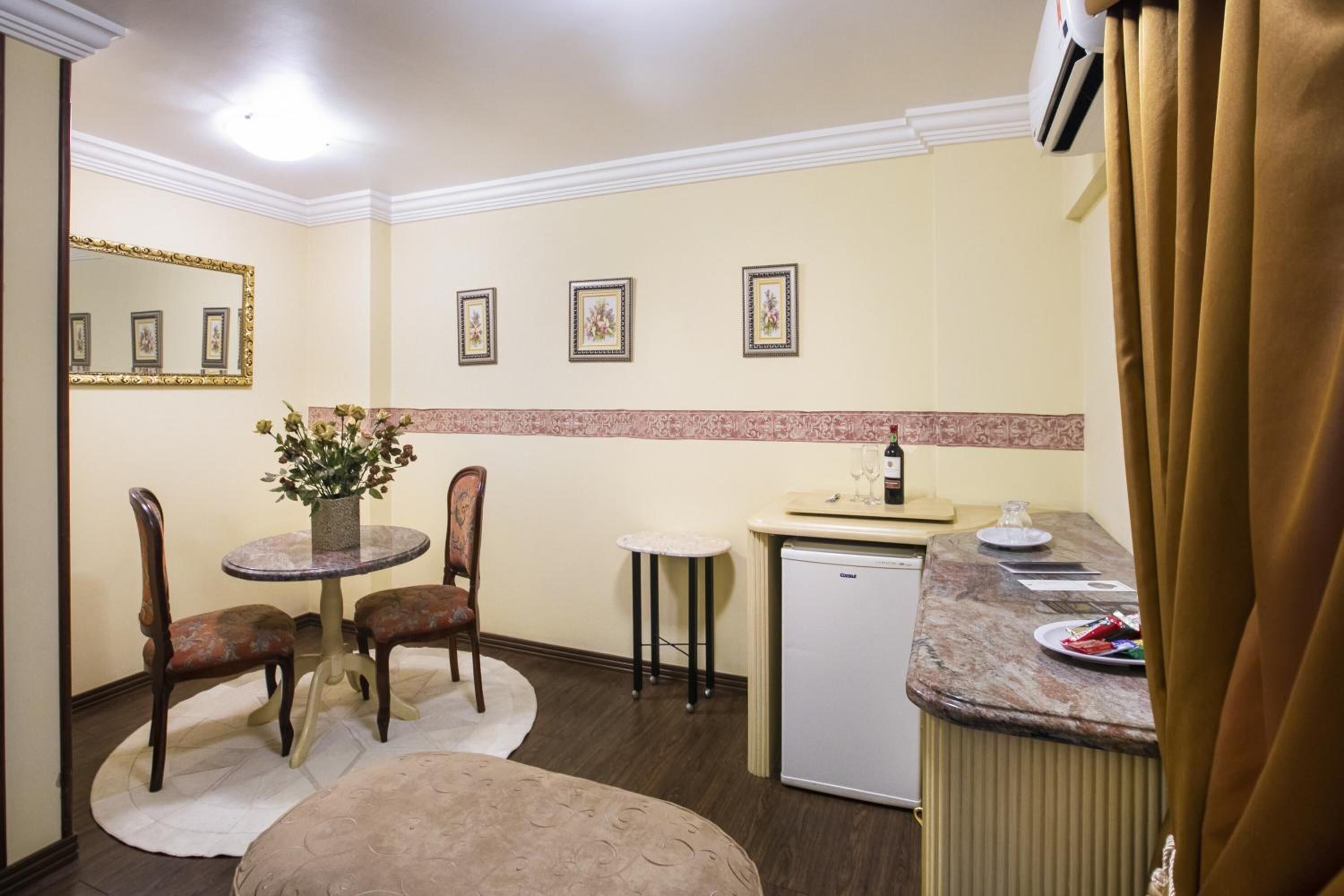 A compact kitchen with a dining table, chairs, a refrigerator, and a small bar area.