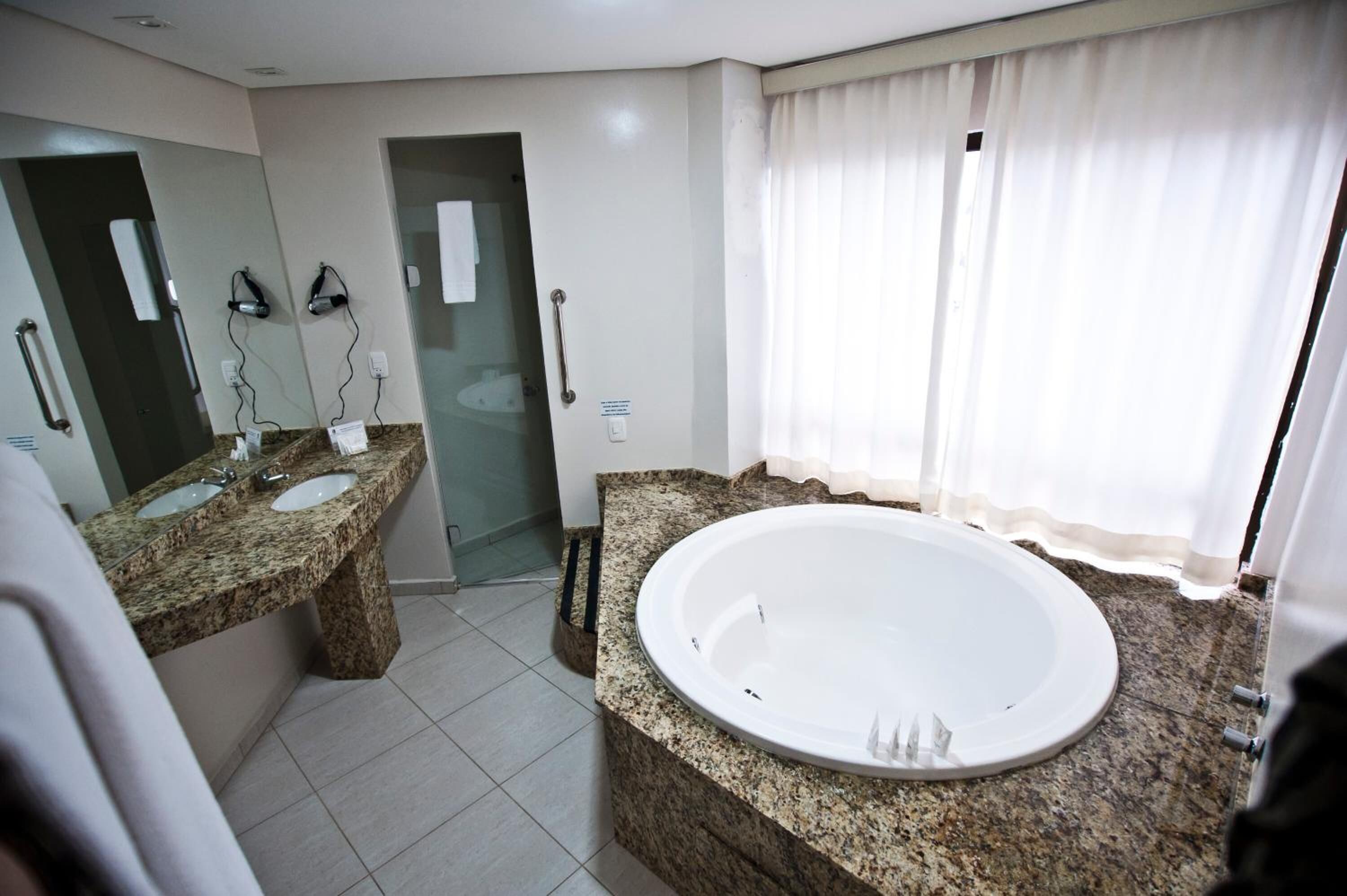 A bathroom with a granite countertop, a large bathtub, and a glass shower enclosure.