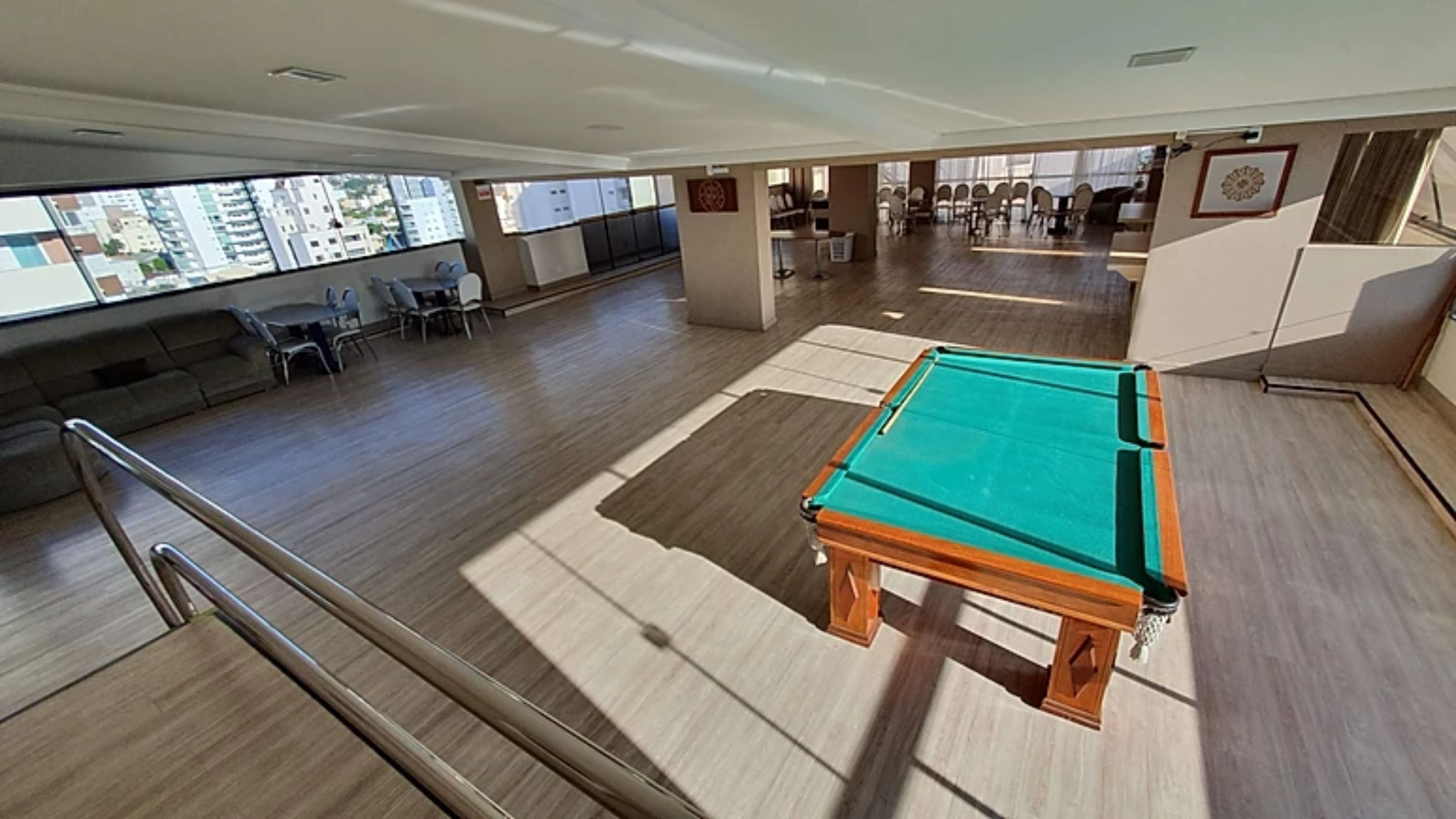 A pool table in a spacious room with a view of the city through large windows.