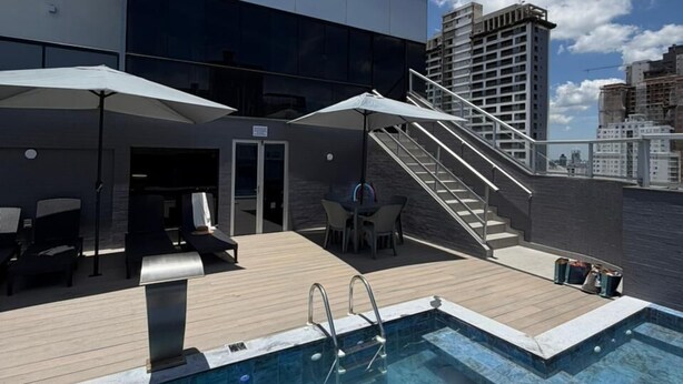 A rooftop pool area with lounge chairs and a staircase leading to an upper level. - Hotel Lang Palace (Chapecó)