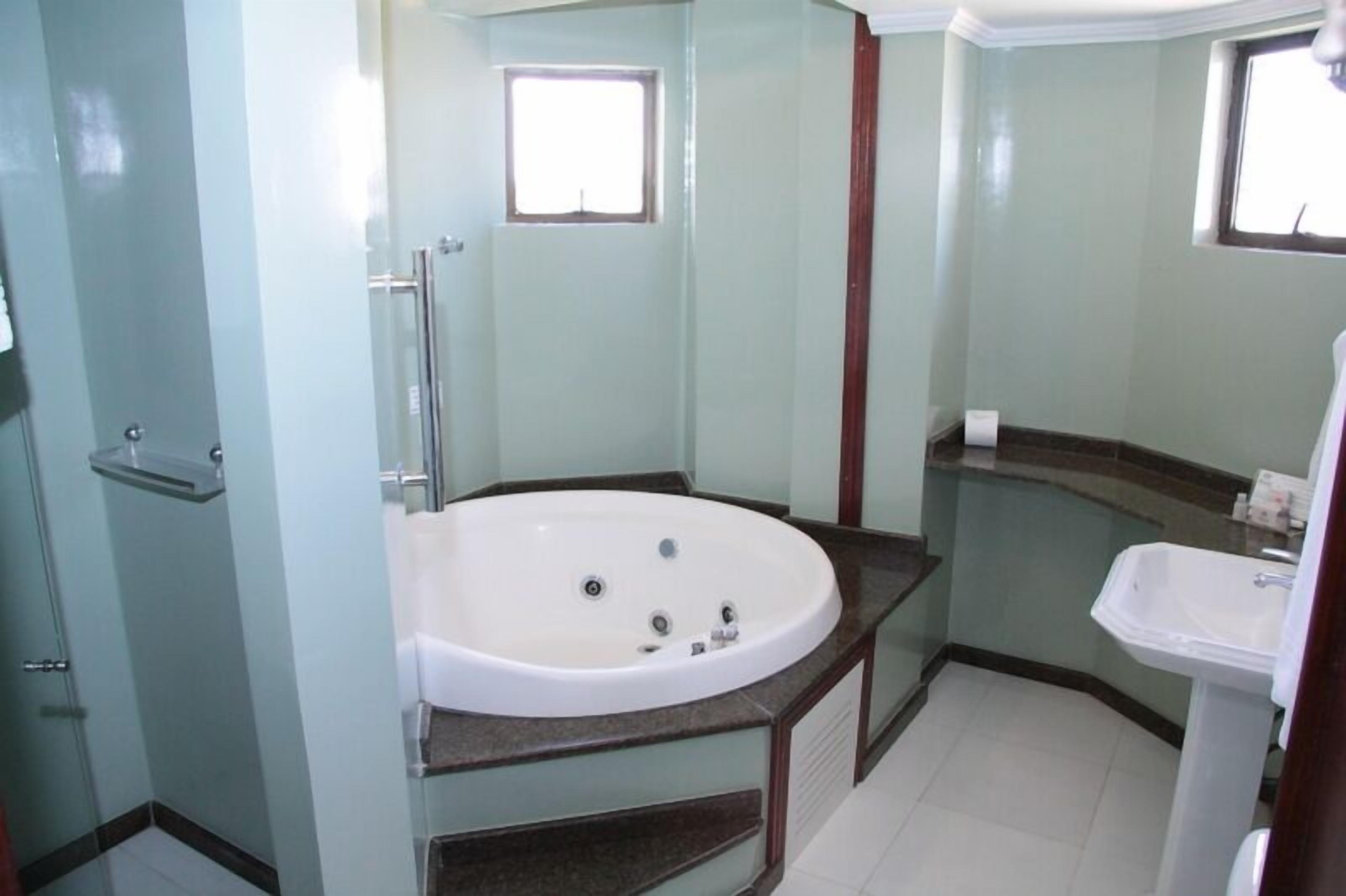 A bathroom with a glass-enclosed shower, a freestanding bathtub, and a pedestal sink.