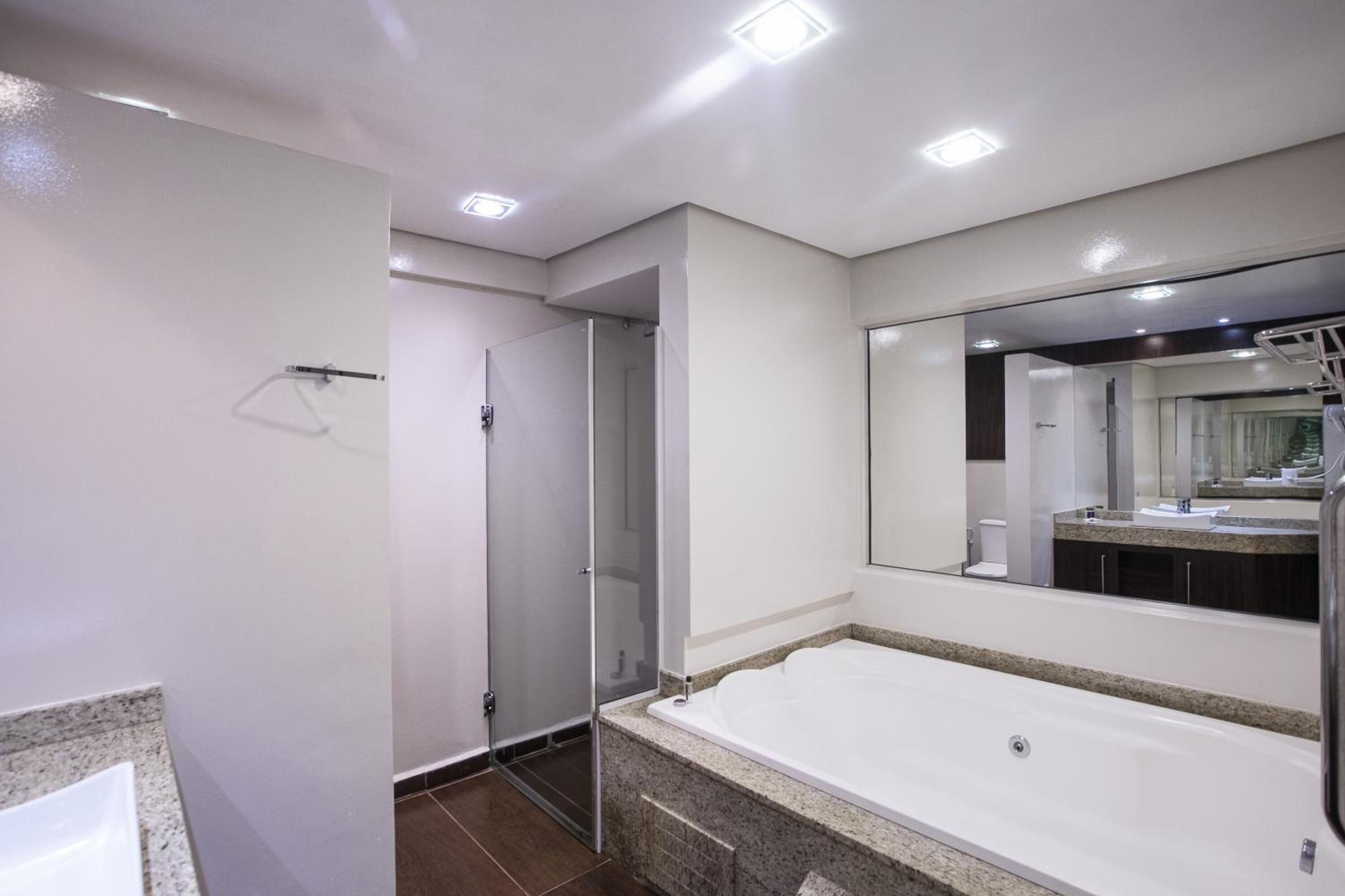 Un baño moderno con una bañera grande, una cabina de ducha de vidrio y un espejo que refleja el baño.