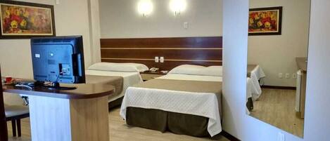 A hotel room with two beds, a desk with a computer, and a large mirror.