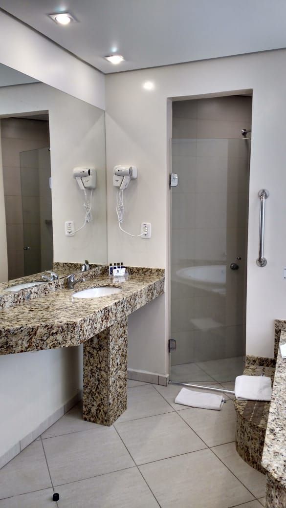 Un baño moderno con lavamanos de granito, cabina de ducha con mampara de vidrio y ducha a ras de suelo.