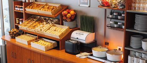 A buffet counter with various food items, including pastries, fruits, and beverages.