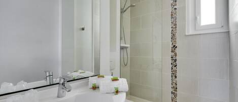 A modern bathroom with a white sink, mirror, and shower.