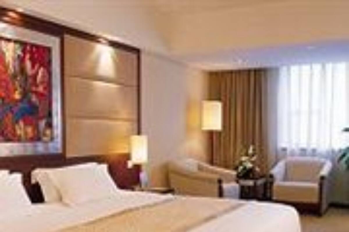 Een hotelkamer met een groot bed, een bureau, een stoel en een schilderij aan de muur.